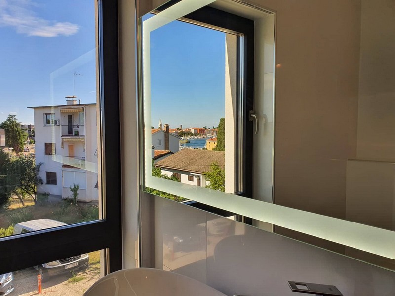 Pohled na moře přes zrcadlo v koupelně.