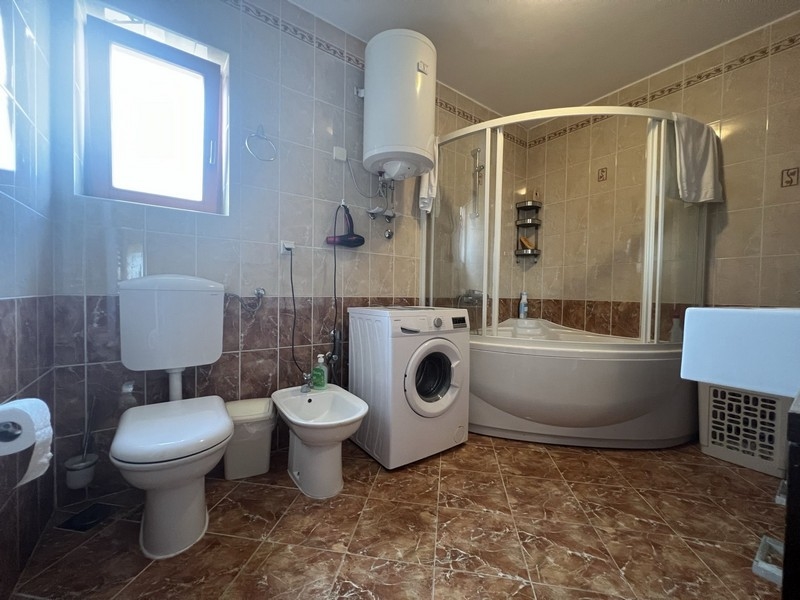 Velká koupelna se sprchovým koutem a pračkou.