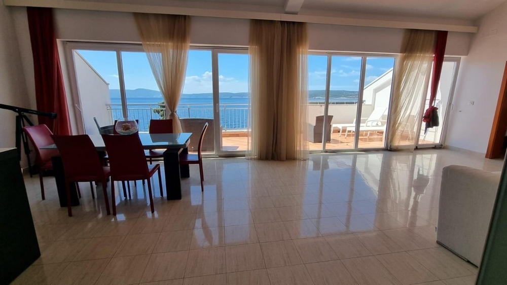 Obývací pokoj s výhledem na terasu a moře.