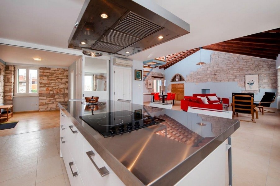 Kvalitní kuchyňský ostrůvek se sporákem a výhledem do středomořského obývacího pokoje.