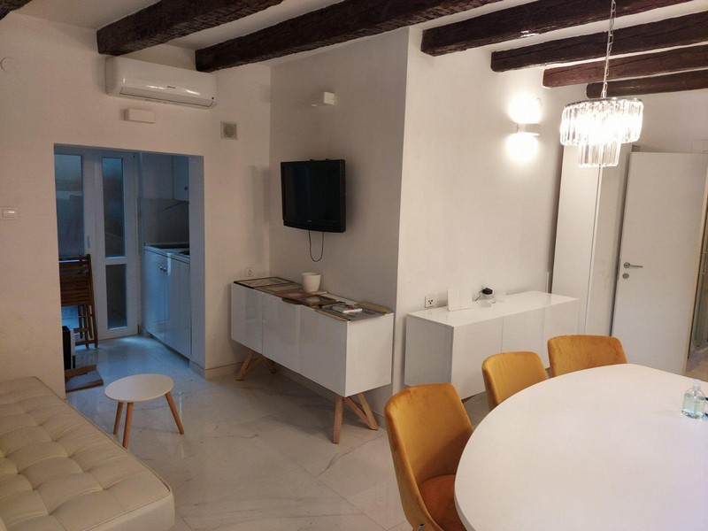 Klimatizovaný obývací pokoj s TV a jídelním koutem a kuchyňským koutem.