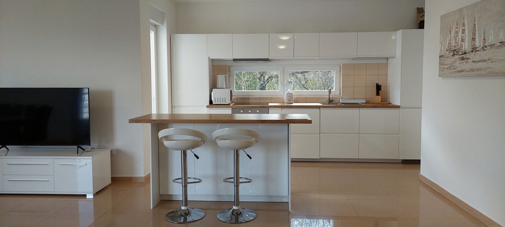 Otevřená kuchyně s barovými židlemi ve vysoce kvalitním apartmánu v Opatiji
