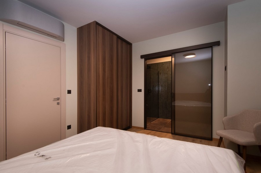 Ložnice s přímým přístupem do koupelny v moderním bytě na prodej ve Splitu v Chorvatsku, s velkou postelí a elegantním nábytkem.