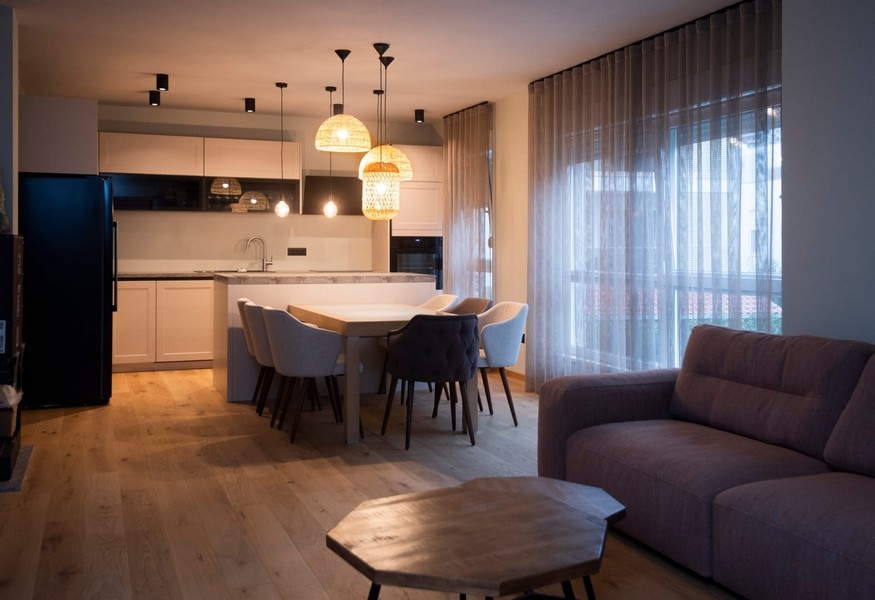 Moderní kuchyně a jídelní kout v bytě na prodej ve Splitu v Chorvatsku se stylovým osvětlením a otevřeným půdorysem.