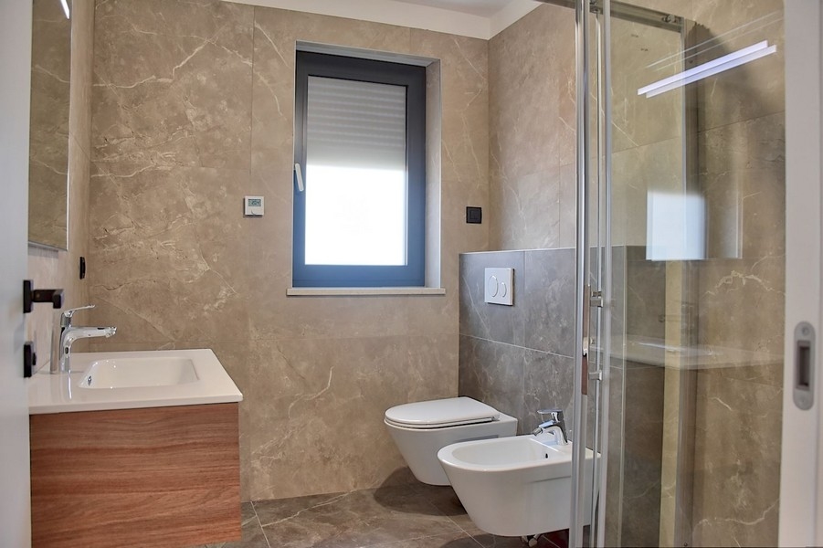 Elegantní koupelna v penthouse na prodej na Istrii s moderním vybavením a mramorovými obklady.