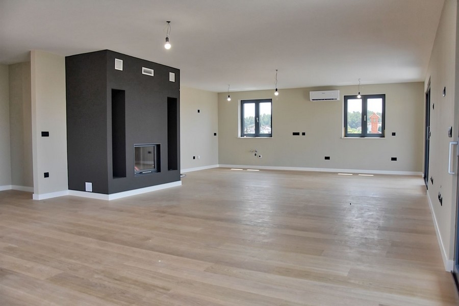 Moderní obývací pokoj v penthouse na prodej na Istrii, s krbem a výhledem na moře.