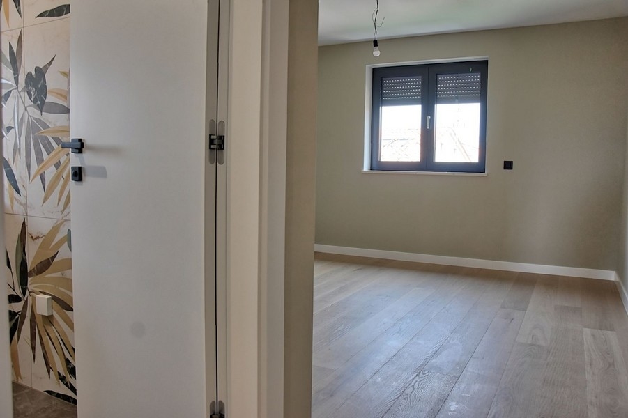 Ložnice v penthouse na prodej na Istrii, s velkými dekorativními obklady a dřevěnými podlahami.