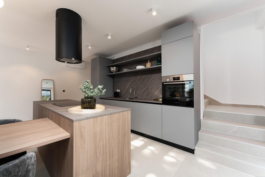 Moderní kuchyně s centrálním varným ostrůvkem a kvalitními vestavěnými spotřebiči v luxusním bytě na Istrii