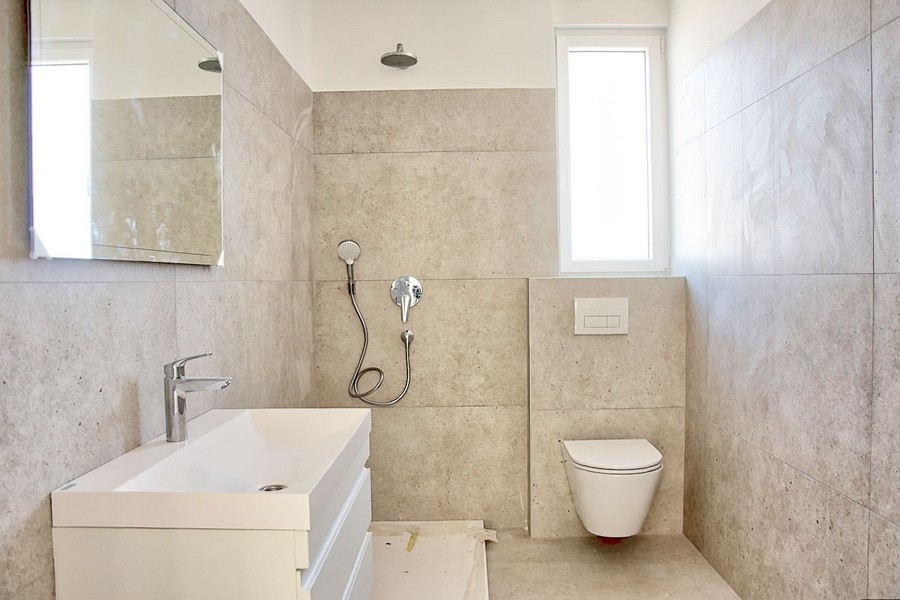 Stylová koupelna s moderním vybavením a jemným kamenným obkladem v luxusním bytě na Istrii