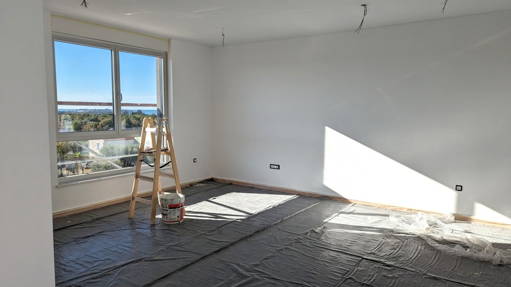 Světlý pokoj v rekonstrukci se žebříkem a malířskými potřebami, součást luxusní nemovitosti na Istrii.