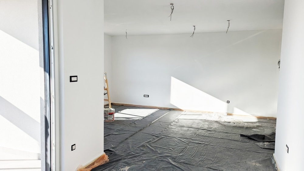 Prostorný, sluncem prosvětlený pokoj s ochrannou fólií na podlaze, v průběhu dokončování prvotřídního bytu na Istrii