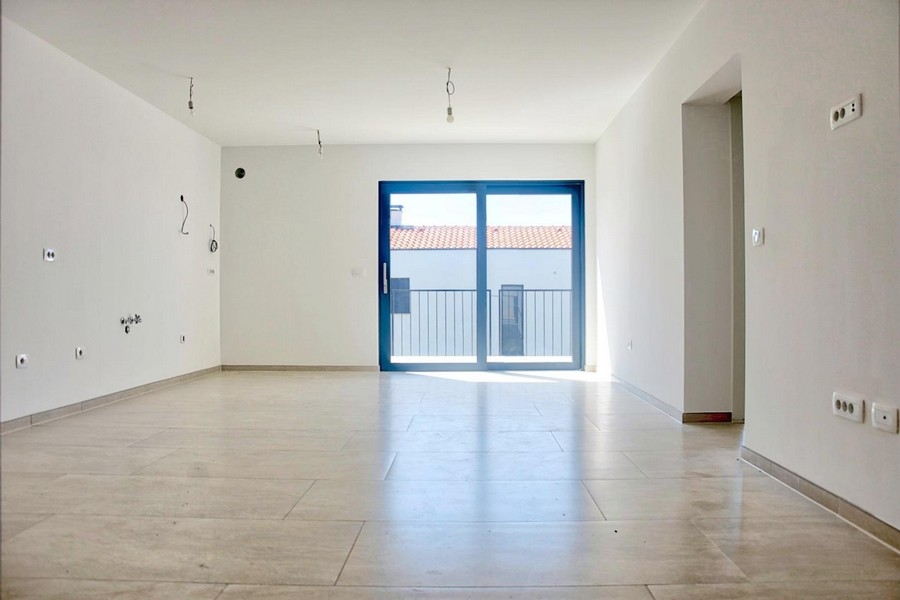 Prázdný světlý obývací pokoj s velkými francouzskými okny a dlažbou, nabídka realit v Poreči