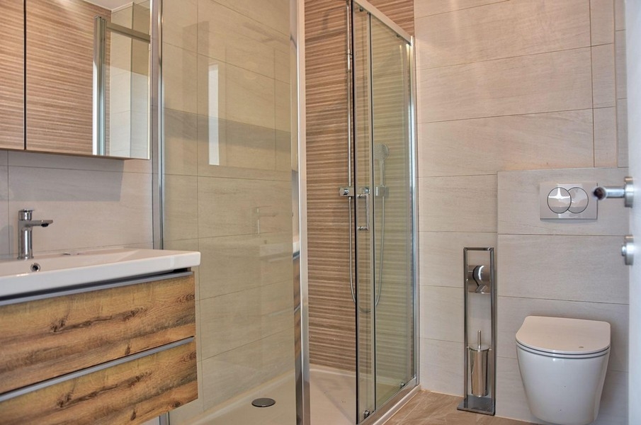 Moderní koupelna se skleněným sprchovým koutem a dřevěnými prvky, nemovitost v Poreči