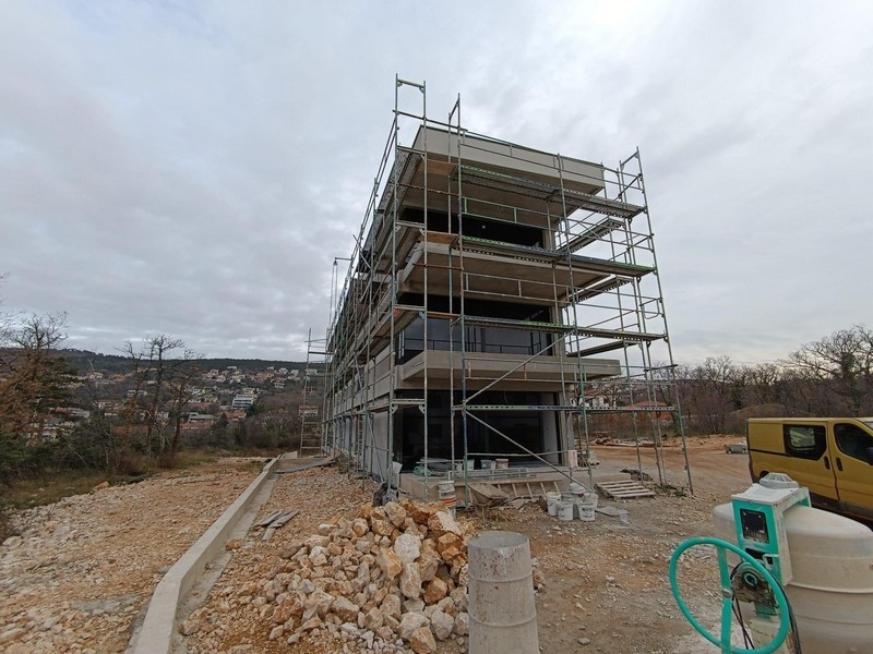 Postup výstavby moderní nemovitosti v Chorvatsku, obklopené lešením a stromy