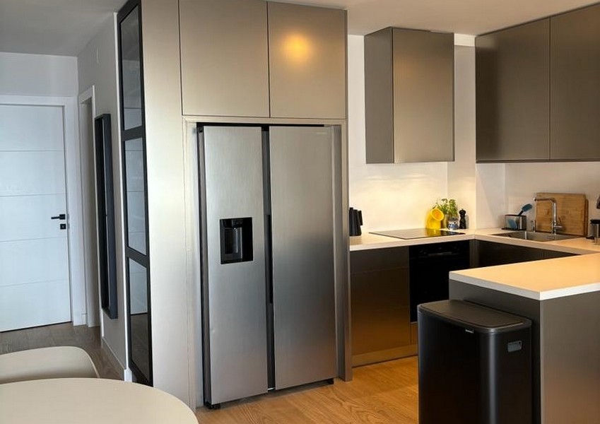 Moderní kuchyně s lednicí z nerezové oceli a tmavými skříněmi, součást nemovitosti v Rijece, Chorvatsko.