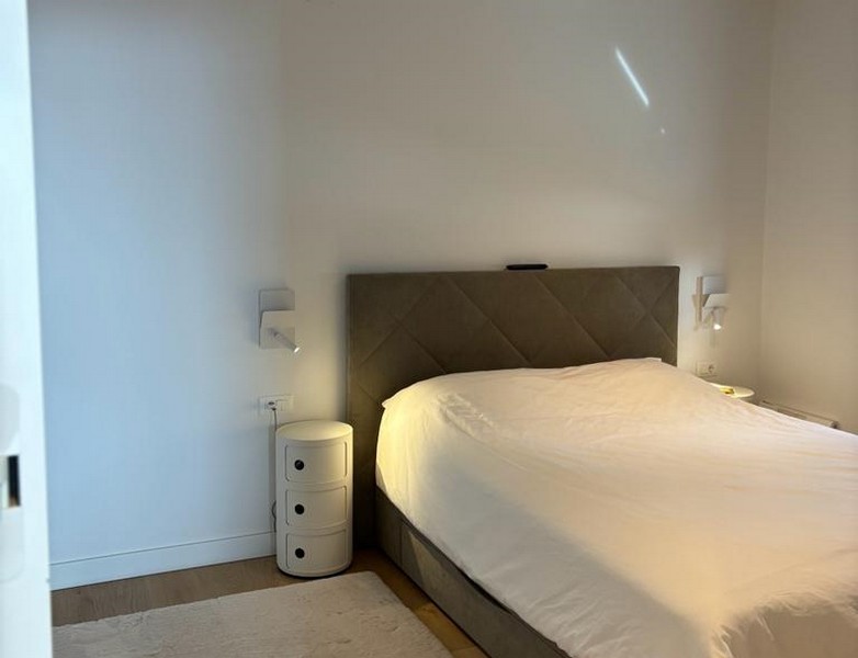 Minimalistická ložnice s velkou postelí a nočním stolkem, součást nemovitosti v Rijece, Chorvatsko.