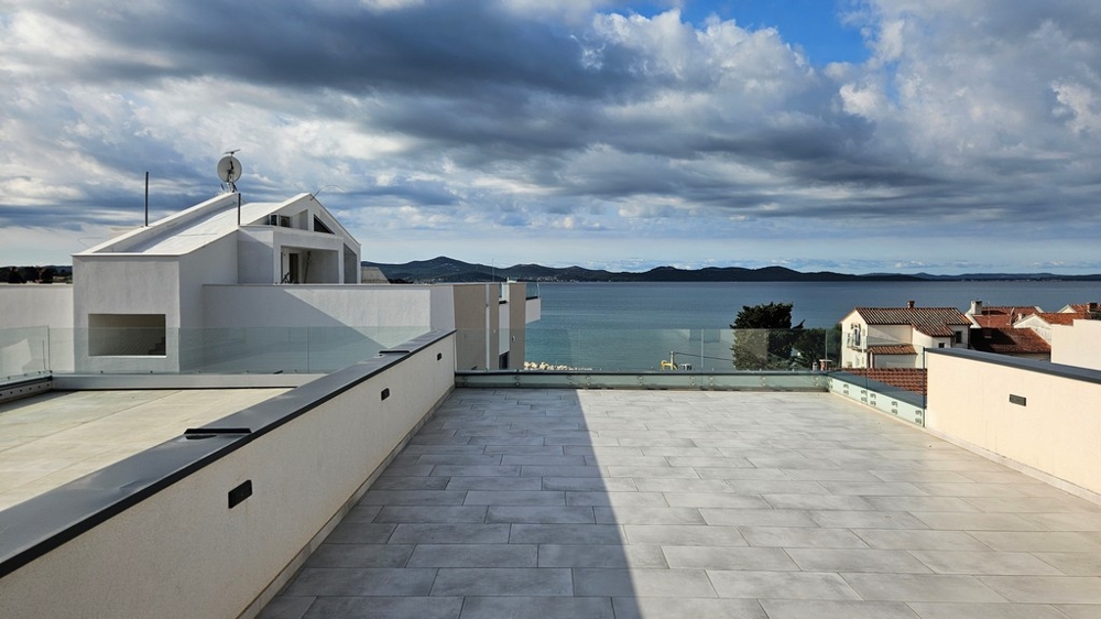 Střešní terasa penthouse na prodej v Zadaru, Chorvatsko, s výhledem na moře a zataženou oblohou
