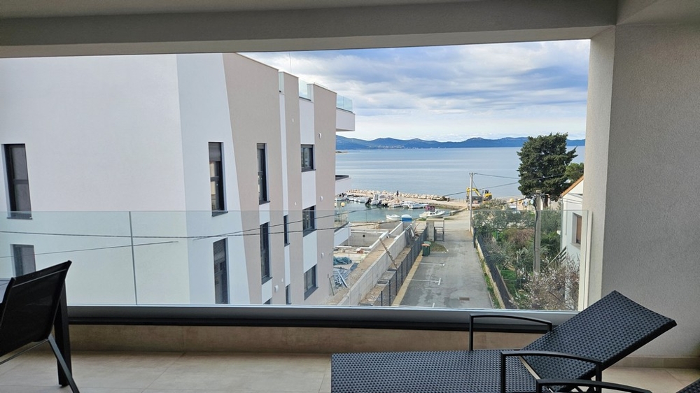 Jídelna se stolem a židlemi v penthouse na prodej v Zadaru, Chorvatsko, s výhledem z okna na moře