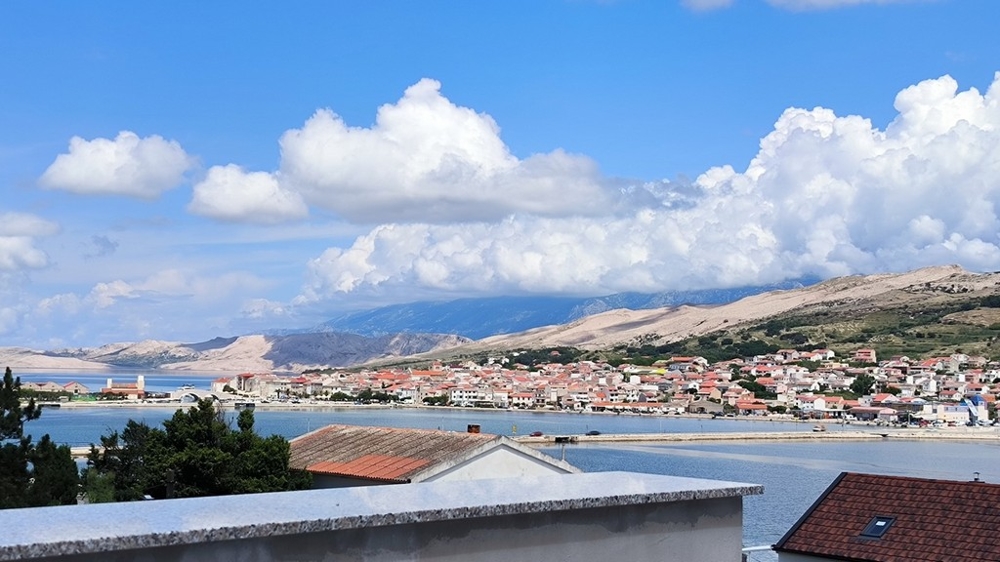 Vnější pohled na parkovací plochu bytu na prodej v Pagu, Chorvatsko, se štěrkovou cestou