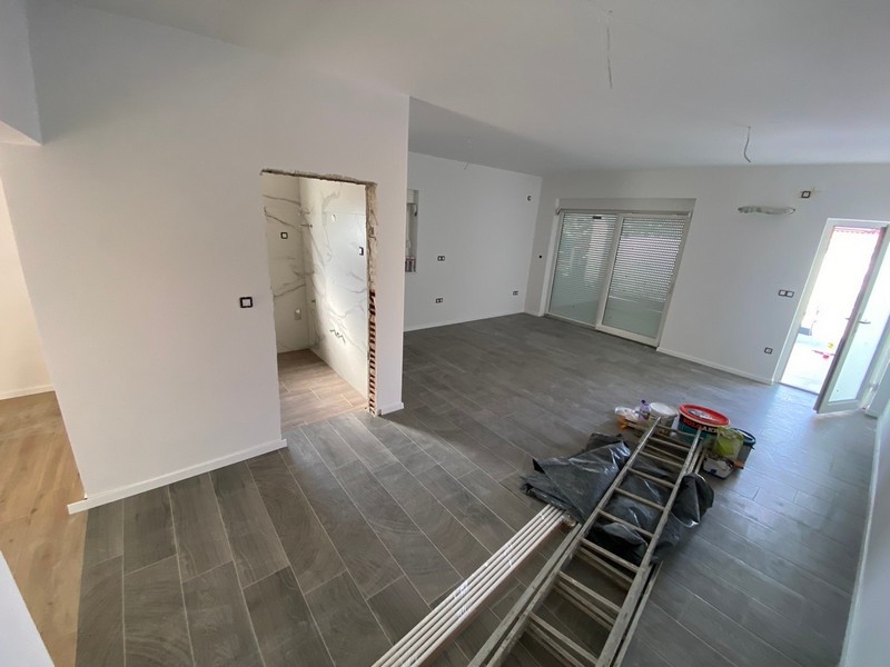 Prázdný obývací prostor s šedou dlážděnou podlahou v bytě na prodej v Pagu, Chorvatsko