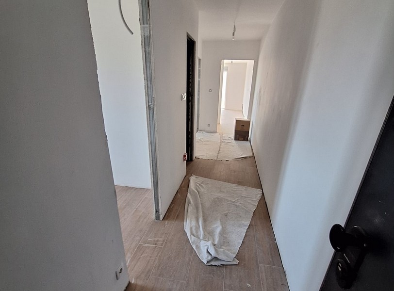 Předsíň v novém bytě, ochranný kryt na podlaze, plášť budovy, světlé stěny, dřevěná podlaha, dveře a pokoje v pozadí, nabídka od Panorama Scouting v Chorvatsku.