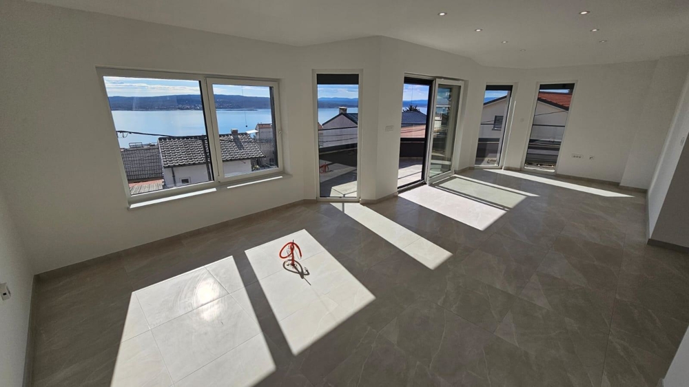 Světlý, prázdný obývací pokoj v bytě na prodej v Crikvenici, Kvarnerský záliv, s velkými okny a výhledem na moře