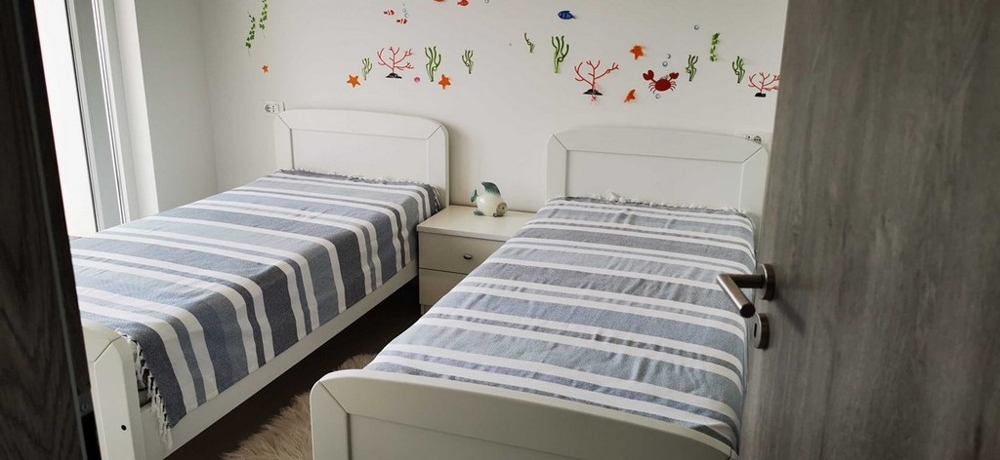 Druhá ložnice se dvěma samostatnými lůžky a veselou nástěnnou dekorací, část bytu na prodej v Tisno, Chorvatsko.