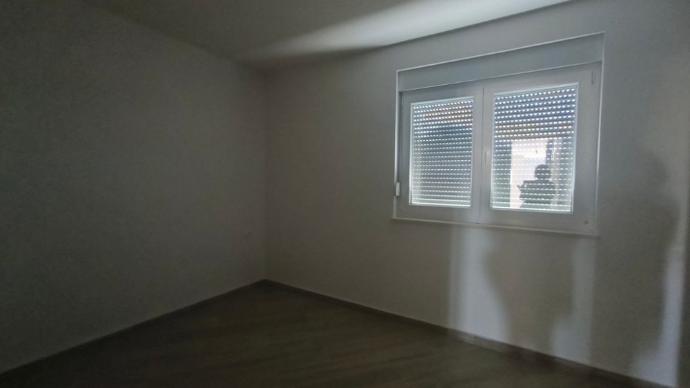 Tmavá místnost v nově postaveném penthouse v Chorvatsku v Šimuni, s oknem a zataženými žaluziemi.