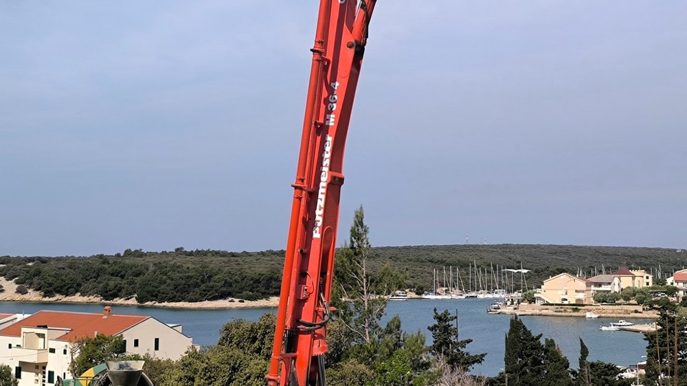 Detailní pohled na červený jeřáb na pozadí malebné Simuni, Chorvatsko nemovitosti s výhledem na moře.