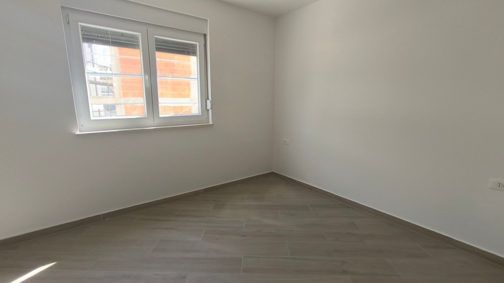 Druhá prázdná ložnice nového střešního bytu v Chorvatsku v Šimuni s velkým oknem.