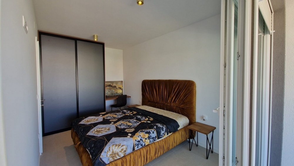 Ložnice apartmánu v Novalji, ostrov Pag, s hnědou postelí a přístupem na balkon, nemovitost Chorvatsko