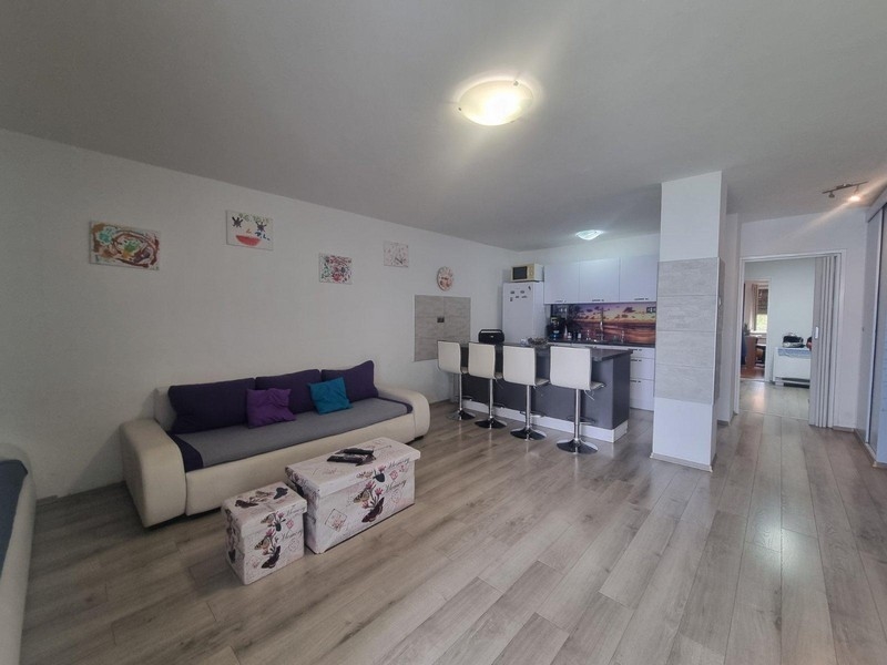 Otevřený obývací prostor s moderním nábytkem a kuchyňským koutem v pozadí