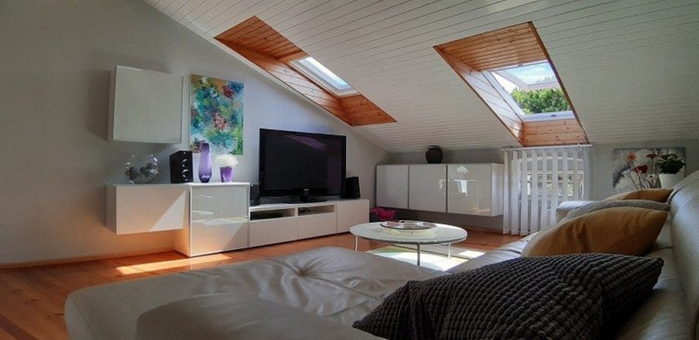 Útulný obývací pokoj se střešními okny, velkou televizí a pohodlnou pohovkou