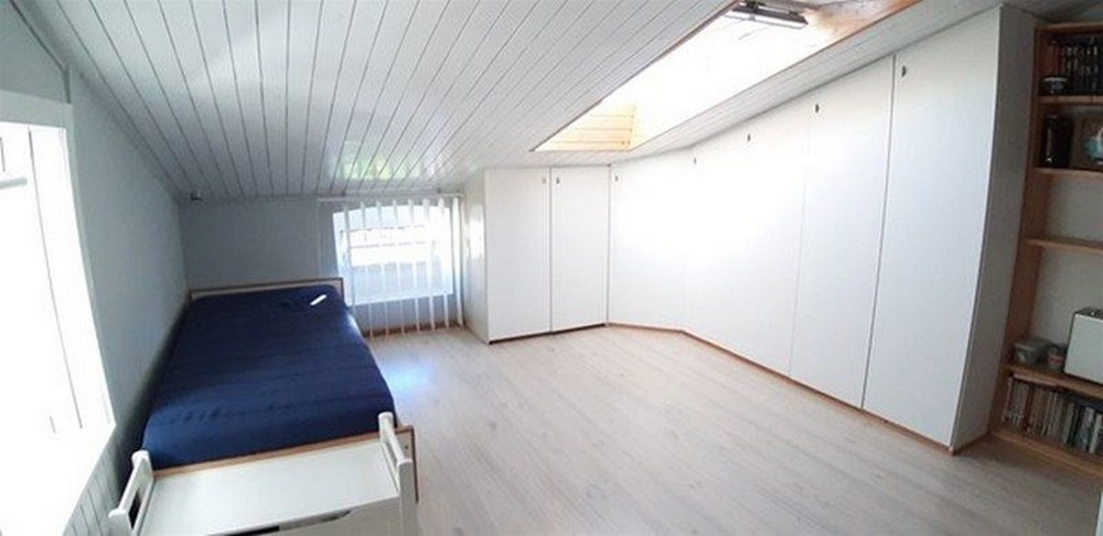 Světlá, minimalistická ložnice se spoustou úložného prostoru a střešním oknem