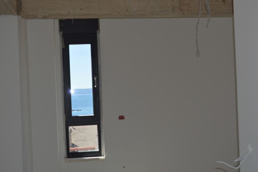 Úzké okno v nedokončeném bytě s výhledem na moře.