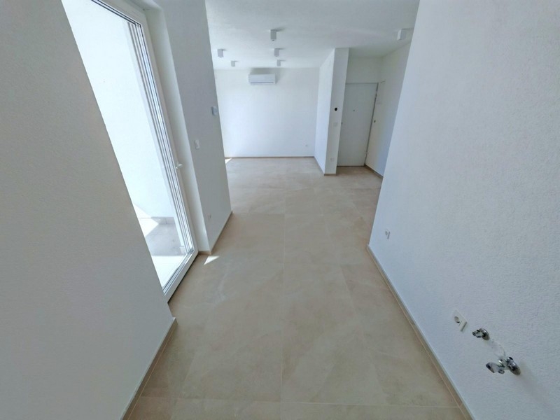 Zadní pohled na bytový dům s parkovacím stáním a zelení ve Smokvici Krmpotské