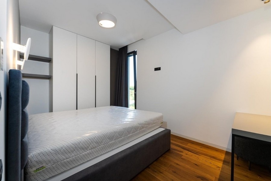 Ložnice s bílými skříněmi, šedá postel, psací stůl