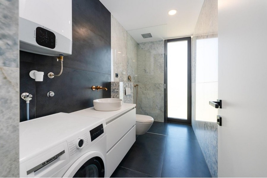 Koupelna s pračkou, bílým umyvadlem, proskleným sprchovým koutem