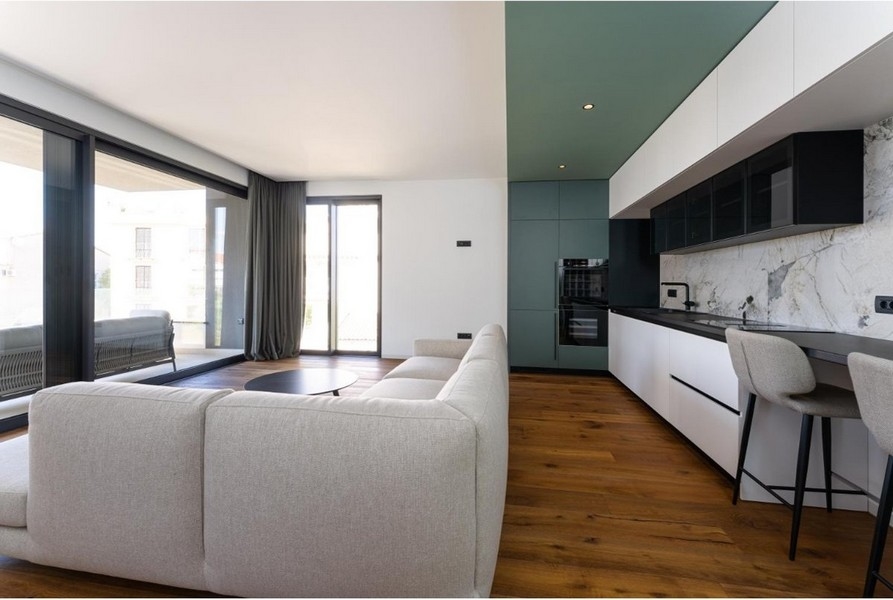 Obývací pokoj s rohovou sedačkou, velká okna, vstup na balkon