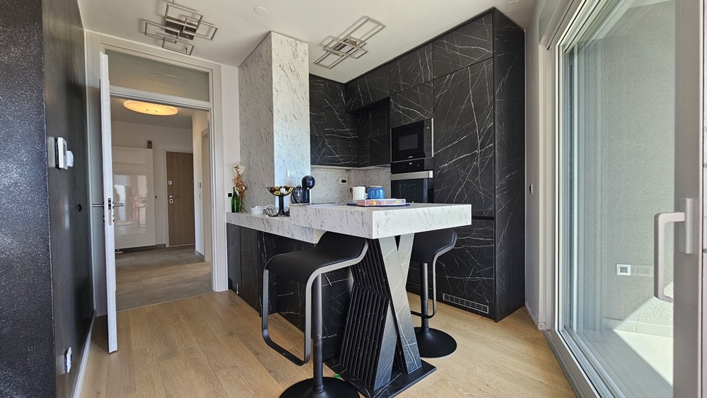 Moderní kuchyně s černým designem a barovými židlemi