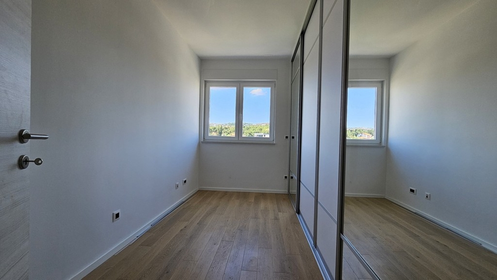 Prázdná místnost s dřevěnou podlahou a vestavěnými skříněmi