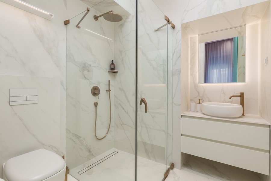 Moderní koupelna s proskleným sprchovým koutem a mramorovými obklady