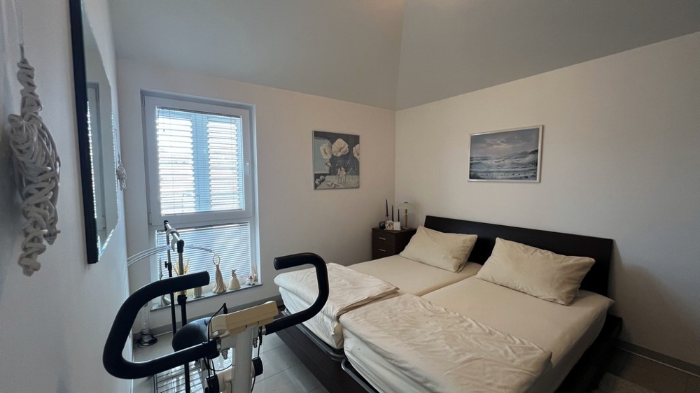 Ložnice se dvěma samostatnými lůžky, rotopedem a minimalistickým nábytkem.