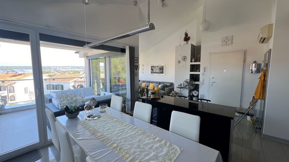 Jídelna a kuchyně s moderním nábytkem, velké okno na terasu s výhledem na moře.