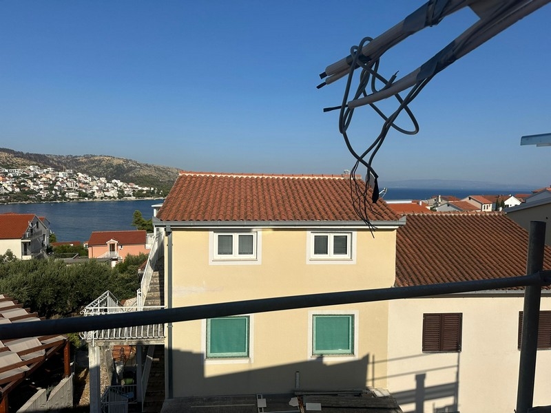 Panoramatický výhled z balkonu ve výstavbě, s výhledem na sousední domy a pobřeží táhnoucí se k obzoru