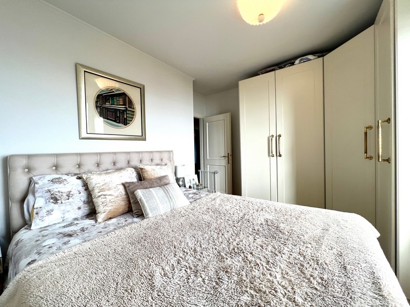 Ložnice s polstrovanou postelí, měkkými přikrývkami a vestavěnými skříněmi