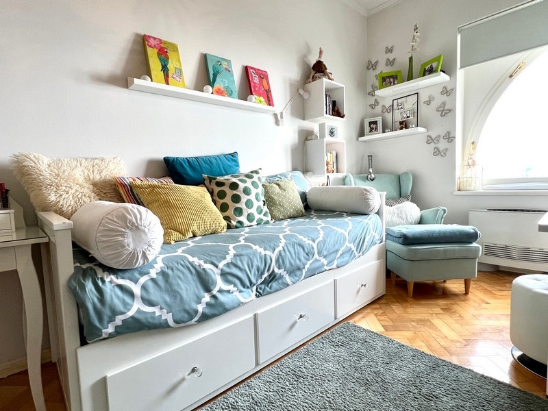 Pokoj pro hosty s denní postelí, dekorativními polštáři a útulným posezením