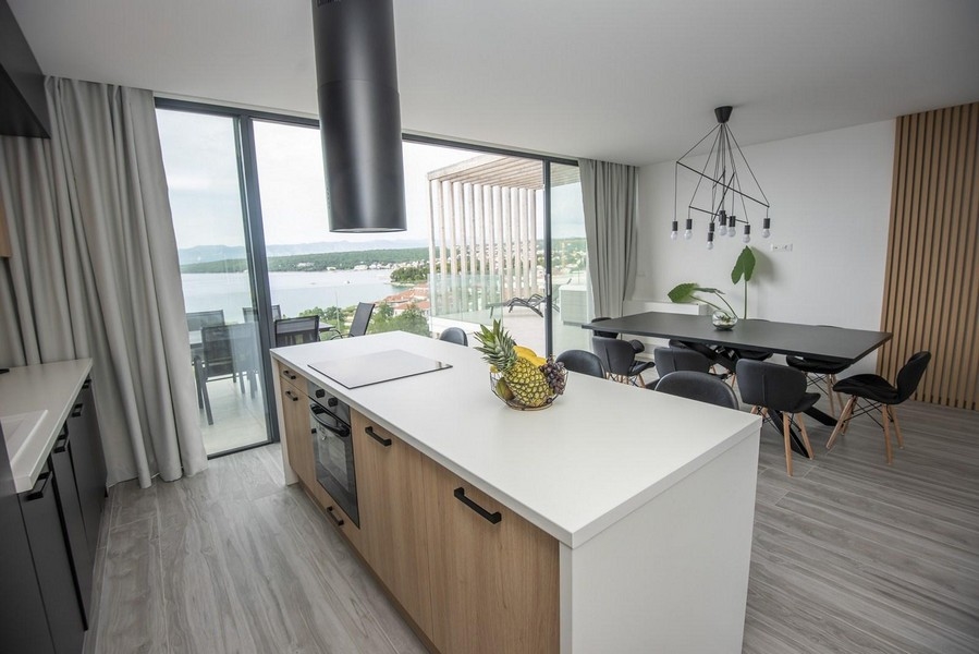 Moderní kuchyně s jídelním stolem a výhledem na moře.