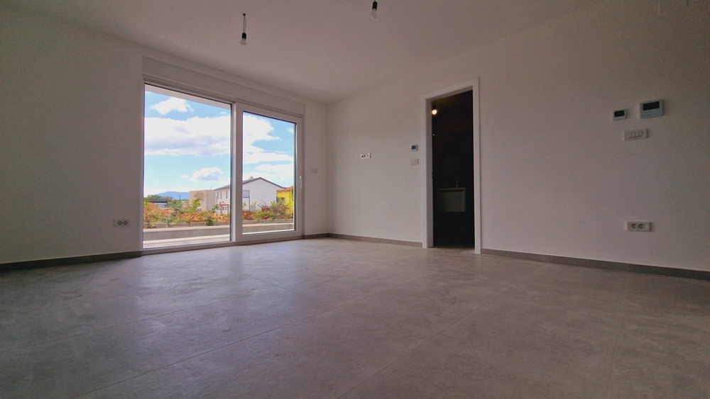 Světlý pokoj s velkými okny a výhledem do zahrady