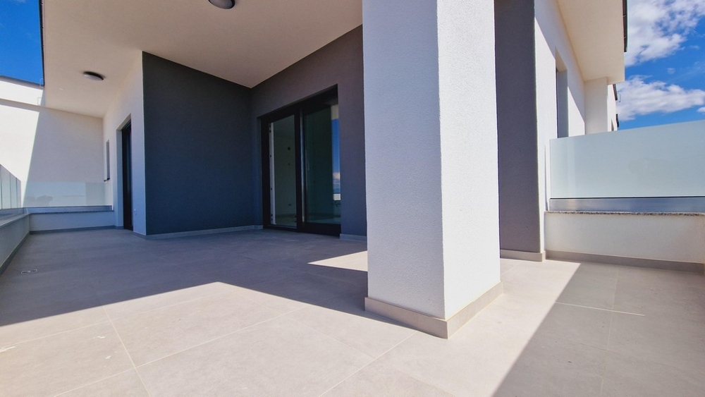 Velká, moderní terasa s bílými sloupy a skleněným zábradlím